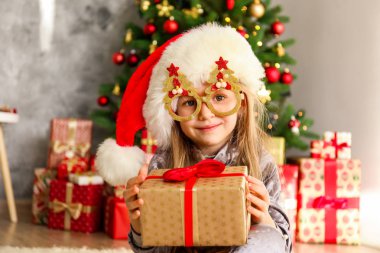 Portre sevimli mutlu beş yaşındaki kızın birçok alan sunar, zemin üzerine sarılmış hediyeler yığını ile süslenmiş Noel ağacı. Yakın çekim, alanı Kopyala.