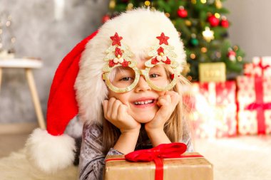 Portre sevimli mutlu beş yaşındaki kızın birçok alan sunar, zemin üzerine sarılmış hediyeler yığını ile süslenmiş Noel ağacı. Yakın çekim, alanı Kopyala.