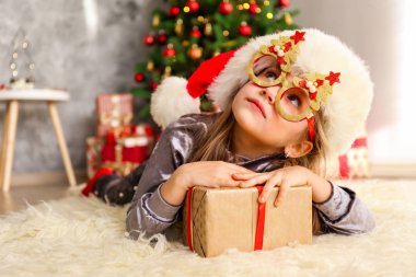 Portre sevimli mutlu beş yaşındaki kızın birçok alan sunar, zemin üzerine sarılmış hediyeler yığını ile süslenmiş Noel ağacı. Yakın çekim, alanı Kopyala.