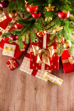Noel ağacı dalları üstten görünüm kompozisyon farklı renkli festival sarma sunar yığını ile yay ile bağlı. Ahşap zemin üzerinde Ladin ağacının altında hediyeler yığını. Arka plan, kopya alanı.