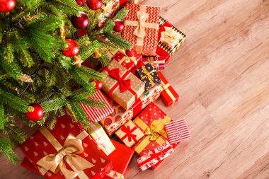 Noel ağacı dalları üstten görünüm kompozisyon farklı renkli festival sarma sunar yığını ile yay ile bağlı. Ahşap zemin üzerinde Ladin ağacının altında hediyeler yığını. Arka plan, kopya alanı.