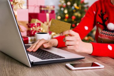 Altın kredi kartı, dizüstü bilgisayar, Noel hediyesi, bir şekilde dekore edilmiş ağaç arka plan üzerinde eller. Malzeme çekme kadın online, eshopping üstünde onu laptop sunar. Ahşap masa, kopya alanı, kapat.