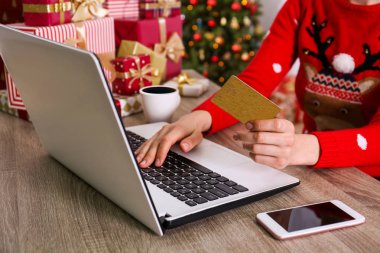 Altın kredi kartı, dizüstü bilgisayar, Noel hediyesi, bir şekilde dekore edilmiş ağaç arka plan üzerinde eller. Malzeme çekme kadın online, eshopping üstünde onu laptop sunar. Ahşap masa, kopya alanı, kapat.