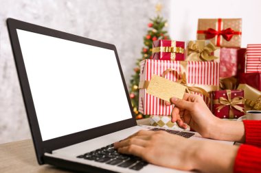 Altın kredi kartı, dizüstü bilgisayar, Noel hediyesi, bir şekilde dekore edilmiş ağaç arka plan üzerinde eller. Malzeme çekme kadın online, eshopping üstünde onu laptop sunar. Ahşap masa, kopya alanı, kapat.