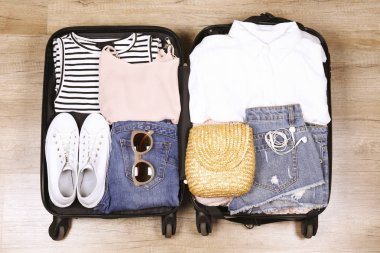 Açık bavul tamamen katlanmış kadın giyim ve aksesuarları yerde ile dolu. Kadın tatil tropikal kavramı için ambalaj. Kadın Bagaj w / şeyler. Arka plan, yakın çekim, uzay, üstten görünüm Kopyala.