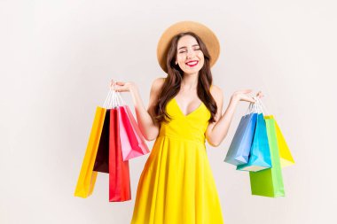İlkbahar Yaz sezonu Satılık kavramı. Seksi sarı elbise giyiyor, birçok farklı boş alışveriş torbaları beyaz arka plan üzerinde tutan çekici genç kadın uzun esmer saçlı. Uzay kopyalayın, yakın çekim.