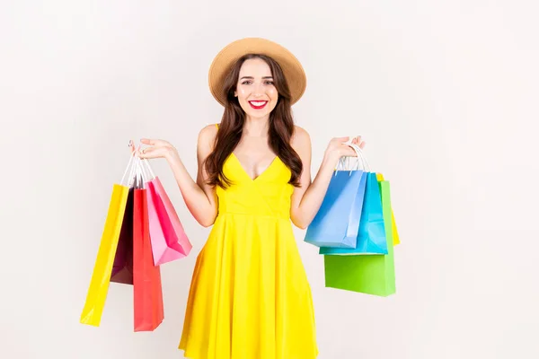 春季夏季销售理念 有吸引力的年轻女子与长黑发 穿着性感的黄色礼服 持有许多不同的空白购物袋在白色的背景 复制空间 — 图库照片
