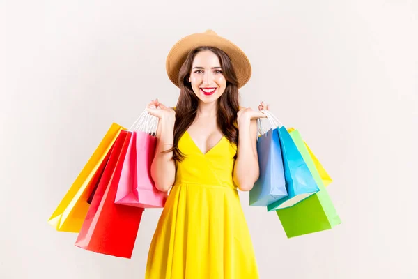 春季夏季销售理念 有吸引力的年轻女子与长黑发 穿着性感的黄色礼服 持有许多不同的空白购物袋在白色的背景 复制空间 — 图库照片