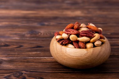 Karışık ahşap kase fındık ve tablo üzerinde dağınık. Ceviz, badem, ceviz fındık ahşap dokulu yüzeyi ile macadamia ve Brezilya yenilebilir fındık karışımı trail. Arka plan, kopya alanı, üstten görünüm, yakın çekim.