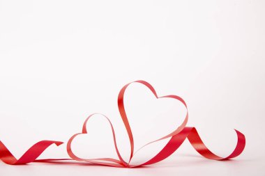 Parlak beyaz arka plan üzerinde kalp şeklinde izole ipek kurdele koydu. Festival dekorasyon. Anne, kadın, evlilik, mutlu st Sevgililer günü kavramı, 14 Şubat. Üstten görünüm, düz yerde kal, yakın çekim.