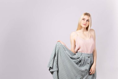 Stüdyo uzun düz saç yumuşak pembe üst ve yenilikçi tam boyu yüksek belli Damalı etek giyen genç sarışın kadınla muhteşem bir kadeh. İzole arka plan gri, uzay kopyalayın, portre, kapatmak.