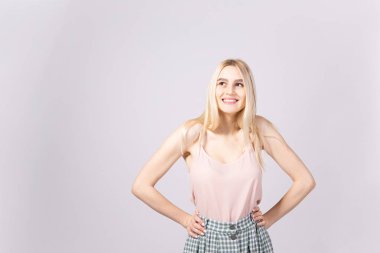 Stüdyo uzun düz saç yumuşak pembe üst ve yenilikçi tam boyu yüksek belli Damalı etek giyen genç sarışın kadınla muhteşem bir kadeh. İzole arka plan gri, uzay kopyalayın, portre, kapatmak.