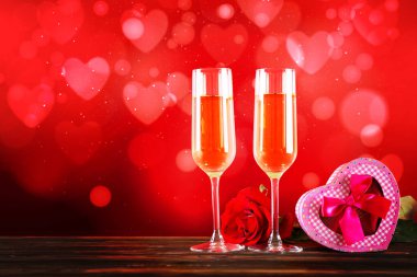 Kırmızı kalp üzerinde iki şampanya flüt gözlüklü kavramsal görüntü bokeh ışıklar şeklinde. Romantik akşam yemeği st Sevgililer günü için. Yakın çekim, alanı Kopyala. Farklı romantik günler için renkli arka plan