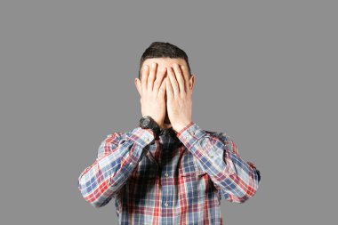 Beden dili kavramı. Yakışıklı delikanlı sakal duygular gösterilen gri duvardan poz ile. Erkeksi sakallı erkek portresi, ince giyen kareli gömlek uygun. İzole arka plan, kopya alanı