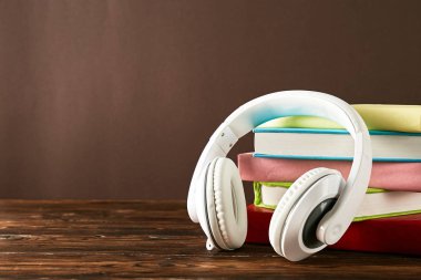 Elektronik audiobook vs normal kağıt kavramı kitap. Tablo boş renkli kapakları ve beyaz kulaklık ile farklı renk ciltli kitap yığını. Eski ve yeni. Yakın çekim, uzay, arka plan kopya.