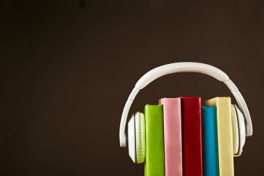 Elektronik audiobook vs normal kağıt kavramı kitap. Tablo boş renkli kapakları ve beyaz kulaklık ile farklı renk ciltli kitap yığını. Eski ve yeni. Yakın çekim, uzay, arka plan kopya.