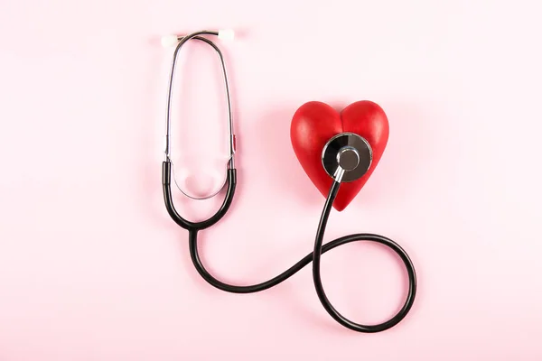 心臓病の認識と予防のコンセプトです コピーのテキストのための領域の多くで淡いピンクの孤立した背景に聴診器と赤の心 クローズ アップ トップ ビュー 心臓医療機器 — ストック写真
