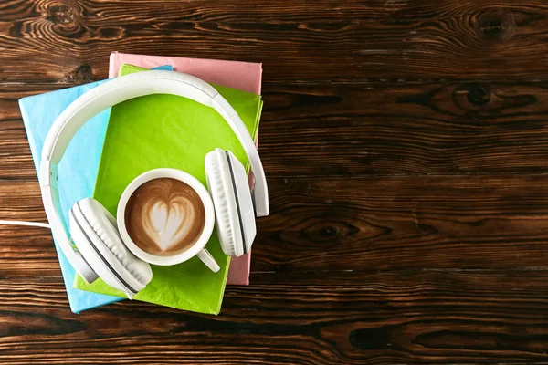 Electronic audiobook vs regular paper book concept. Stack of different color hardcover books with blank colorful covers & white headphones on table. Old versus new. Close up, copy space, background.