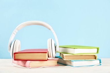 Elektronik audiobook vs normal kağıt kavramı kitap. Tablo boş renkli kapakları ve beyaz kulaklık ile farklı renk ciltli kitap yığını. Eski ve yeni. Yakın çekim, uzay, arka plan kopya.