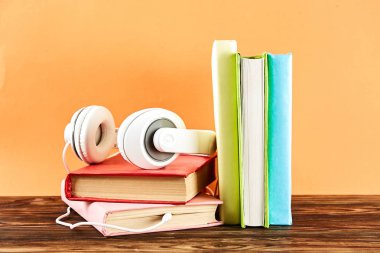 Elektronik audiobook vs normal kağıt kavramı kitap. Tablo boş renkli kapakları ve beyaz kulaklık ile farklı renk ciltli kitap yığını. Eski ve yeni. Yakın çekim, uzay, arka plan kopya.