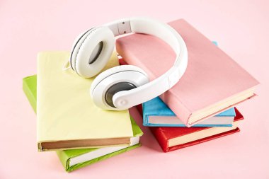 Elektronik audiobook vs normal kağıt kavramı kitap. Tablo boş renkli kapakları ve beyaz kulaklık ile farklı renk ciltli kitap yığını. Eski ve yeni. Yakın çekim, uzay, arka plan kopya.