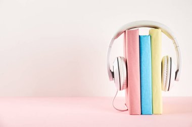 Elektronik audiobook vs normal kağıt kavramı kitap. Tablo boş renkli kapakları ve beyaz kulaklık ile farklı renk ciltli kitap yığını. Eski ve yeni. Yakın çekim, uzay, arka plan kopya.