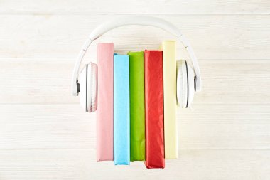 Elektronik audiobook vs normal kağıt kavramı kitap. Tablo boş renkli kapakları ve beyaz kulaklık ile farklı renk ciltli kitap yığını. Eski ve yeni. Yakın çekim, uzay, arka plan kopya.