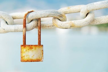 Vintage paslı asma kilit zinciri bağlantı tropikal hedef Koyu'ndaki asılı dock Dağları ile bulanık deniz kıyısında manzaralı. Grunged kilit ile kopya alanı metin için. Yakın çekim.