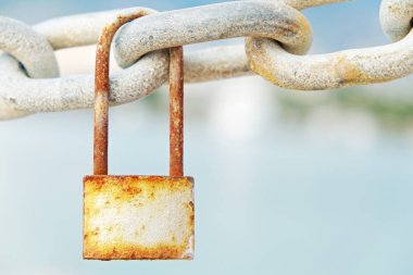 Vintage paslı asma kilit zinciri bağlantı tropikal hedef Koyu'ndaki asılı dock Dağları ile bulanık deniz kıyısında manzaralı. Grunged kilit ile kopya alanı metin için. Yakın çekim.