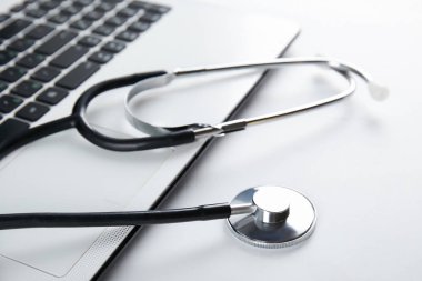 Modern tıbbi teknoloji ve yazılım gelişmeler kavram. Doktor çalışma tablosunu stetoskop akustik cihazla dizüstü bilgisayar klavye kapatın. Kopyalama alanı, arka plan, üstten görünüm, düz yatıyordu.