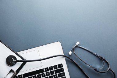 Modern tıbbi teknoloji ve yazılım gelişmeler kavram. Doktor çalışma tablosunu stetoskop akustik cihazla dizüstü bilgisayar klavye kapatın. Kopyalama alanı, arka plan, üstten görünüm, düz yatıyordu.