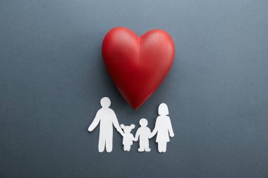 Aile Sağlığı / hayat sigortası kavramı. Zinciri içinde biçim-in aile, Anne, Baba, oğlu ve kızı ile büyük kırmızı kalp seramik gri arka plan üzerinde rakam kağıt. Üstten görünüm, düz yerde kal, kopya alanı, yakın çekim