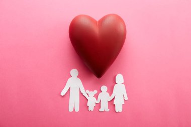 Aile Sağlığı / hayat sigortası kavramı. Zinciri içinde biçim-in aile, Anne, Baba, oğlu ve kızı ile büyük kırmızı kalp seramik, pembe arka plan rakam kağıt. Üstten görünüm, düz yerde kal, kopya alanı, yakın çekim