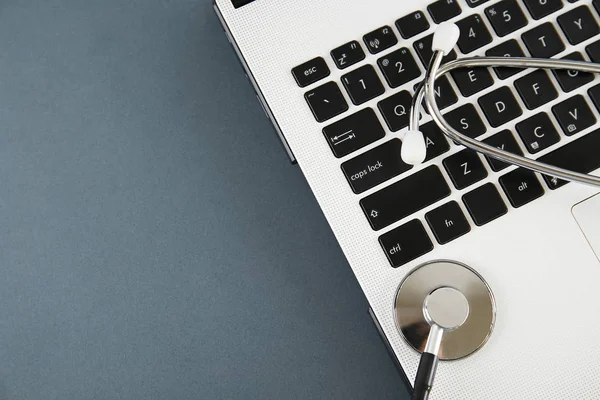 Modern medical technology and sofware advances concept. Doctor\'s working table with stethoscope acoustic device, laptop computer keyboard close up. Copy space, background, top view, flat lay.