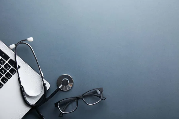 Modern medical technology and sofware advances concept. Doctor\'s working table with stethoscope acoustic device, laptop computer keyboard close up. Copy space, background, top view, flat lay.