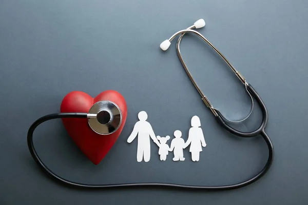Aile Sağlığı / hayat sigortası kavramı. Aile, Anne, Baba, oğlu ve kızı şeklinde kağıt zinciri. Akustik stetoskop tıbbi cihaz gri arka plan üzerinde. En iyi görünüm düz yatıyordu, alanı kopyalayın, yakın çekim