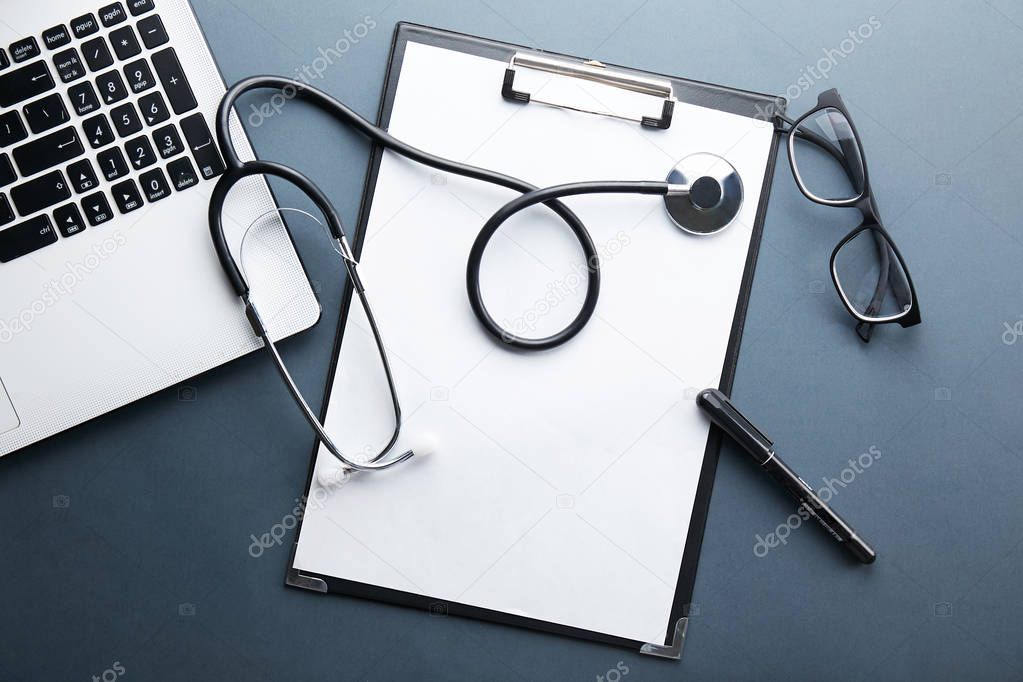 Modern medical technology and sofware advances concept. Doctor's working table with stethoscope acoustic device, keyboard, blank medical record. Close up, copy space background, top view, flat lay.