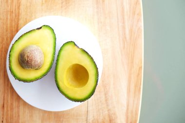 Beyaz mermer coaster ile yarıya besin yoğun avokado meyve dilimleri kalp sağlıklı tekli doymamış yağ gri cam masa üstü dolu. Yakın çekim, kopya alanı, üstten görünüm, arka plan.