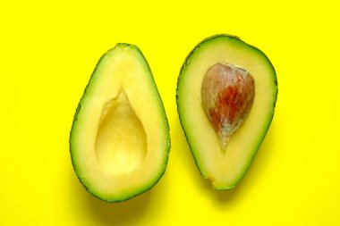 En az kompozisyon ile yarıya besin yoğun avokado meyve dilimleri dolu kalp sağlıklı tekli doymamış yağ parlak sarı zemin üzerine metin için kopya yer ile. Yakın çekim, görünümü top.