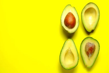 Minimal composition with halved nutrient dense avocado fruit slices full of heart healthy monounsaturated fat on bright yellow background with copy space for text. Close up, top view. clipart