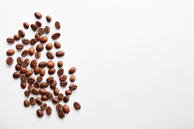 Metin için bir sürü yer Kopyala ile beyaz tabloda kavrulmuş kahverengi kahve çekirdekleri dağınık. Düz yatıyordu kompozisyon. Yakın çekim, görünümü, arka plan top.