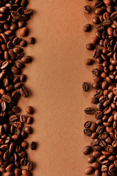 Freshly roasted coffee beans scattered on brown table with a lot copy space for text. Flat lay composition. Close up, top view, background.