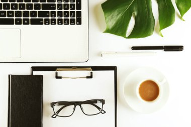 Kadın Blog yazar çalışma konsepti. Femenine masaüstü kompozisyon üzerinde büyük yeşil Monstera palmiye yaprağı. Arka plan, yakın çekim, kopya alanı, düz yatıyordu, üst görünüm.