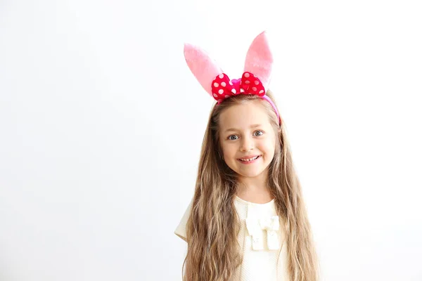 Chica sonriente con orejas de conejo, fondo de espacio de copia de pared blanca . — Foto de Stock