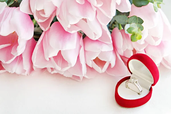 Close up composition with luxurious diamond ring and beautiful bouquet of pink tulips. — Stock Photo, Image