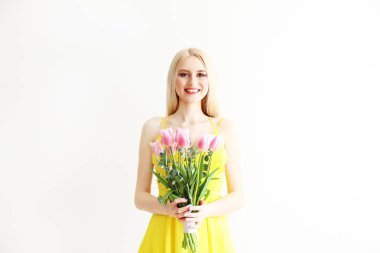 Çiçeklerle gri arka plan üzerinde poz çekici genç kadın.
