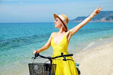 Genç ve güzel bir kadın bisikletle deniz manzarasının tadını çıkarıyor..