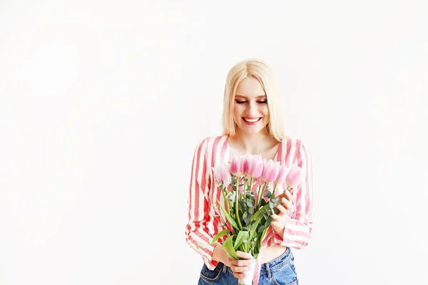 Mladý blondýnka žena v maminka džíny a plodina top shirt držení kytice tulipánů. — Stock fotografie