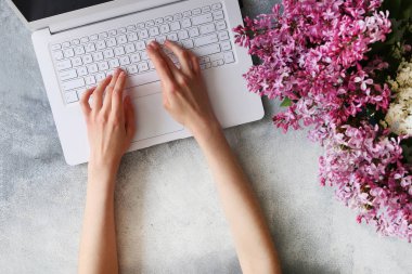 Çiçek ve elektronik cihazlar ile dokulu masa üzerinde Kadın eller.