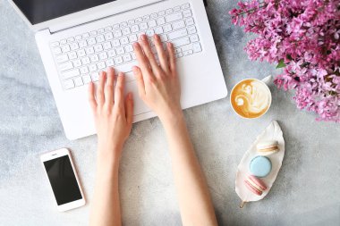 Çiçek ve elektronik cihazlar ile dokulu masa üzerinde Kadın eller.